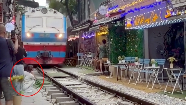 Cô gái ngồi cà phê đường tàu bị tàu hỏa hất văng điện thoại, suýt cuốn vào gầm