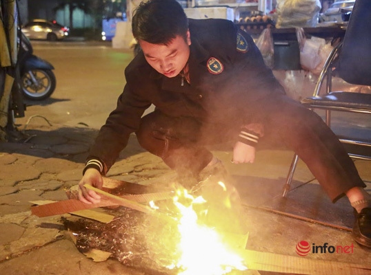 A security officer adds pieces of wood onto the bonfire.