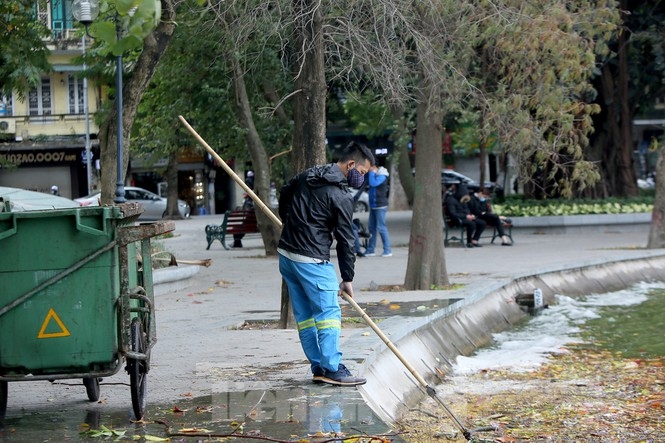 Workers are forced to don extra layers while they collect rubbish on the banks of Ho Guom.