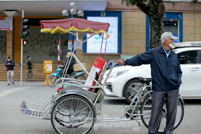 Trung, who has worked as a cyclo driver for 10 years, has to wait for two hours due to there being no customers because of the cold weather.