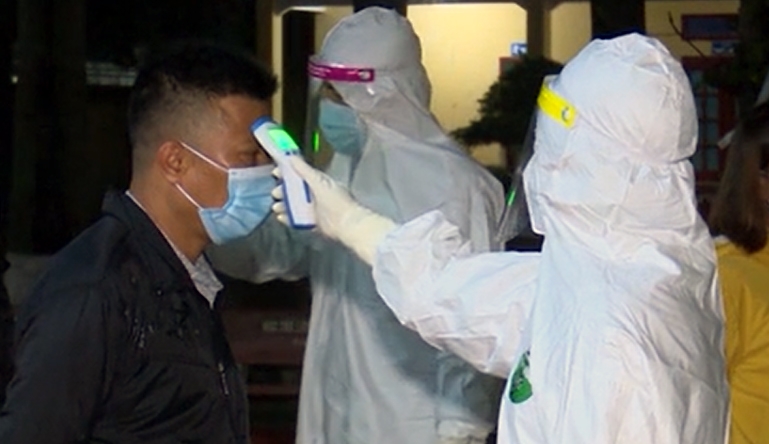 Checking a local resident's body temperature in Hai Duong province, the epicentre of the country's fresh outbreak.