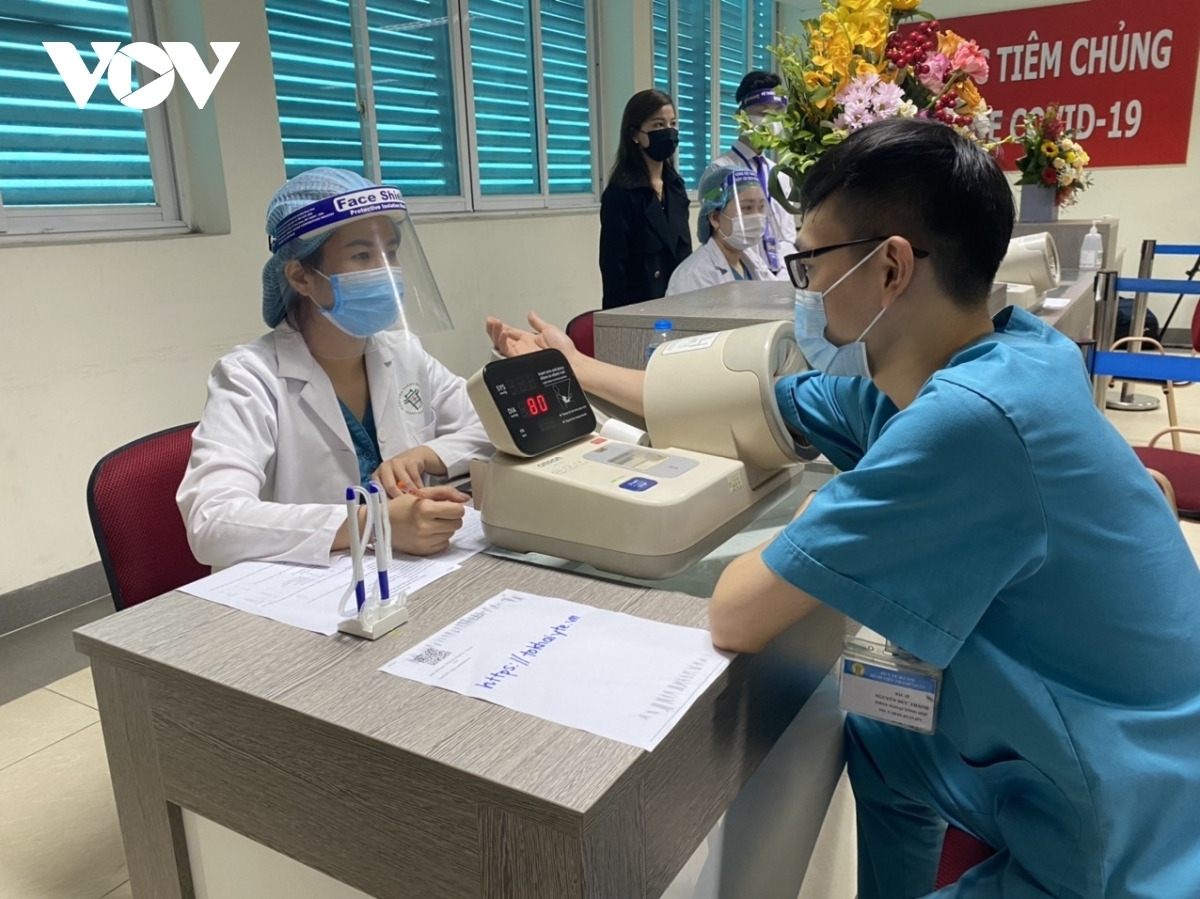 A healthcare worker has his health checked before getting a vaccine shot.