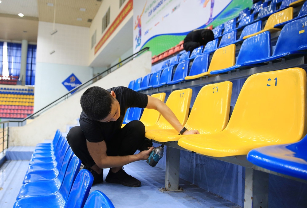 A worker is finalizing seat repair at the Gia Lam competition hall, the venue of the wrestling event.