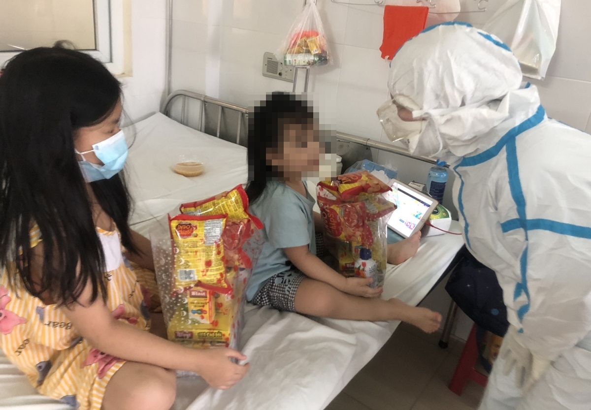 Doctors wearing protective gear offer gifts to the children.