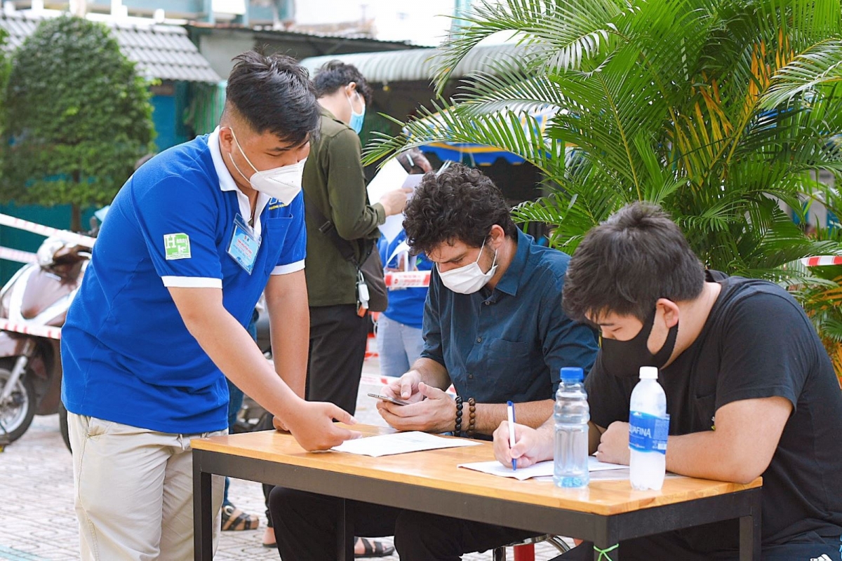 A volunteer in ward 1 of Tan Binh district instructs foreigners to fill in their healthcare declaration forms ahead of getting vaccinated against COVID-19.