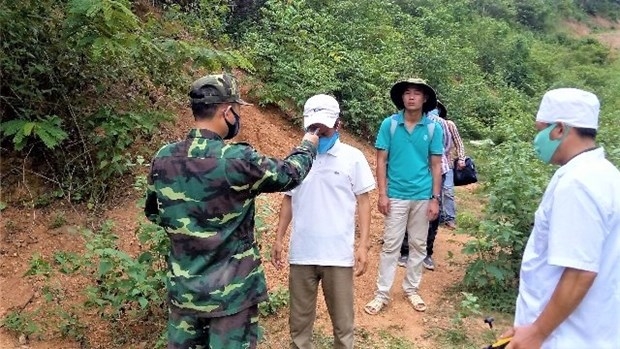 A border guard checks body temperature of people (Illustrative photo: phapluatvamoitruong.vn)