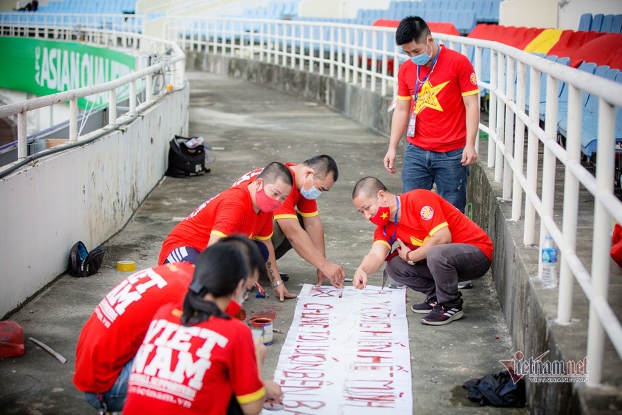 Fans paint words on their banners to support the team.