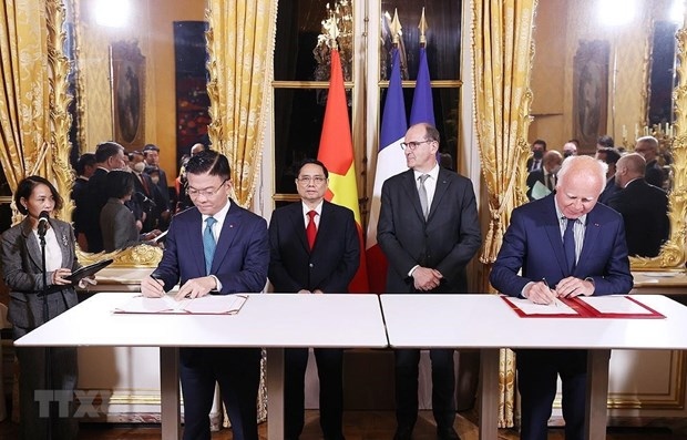 Prime Minister Pham Minh Chinh (behind, L) and his French counterpart Jean Castex witness the signing ceremony of cooperation documents between the two countries. (Photo: VNA)