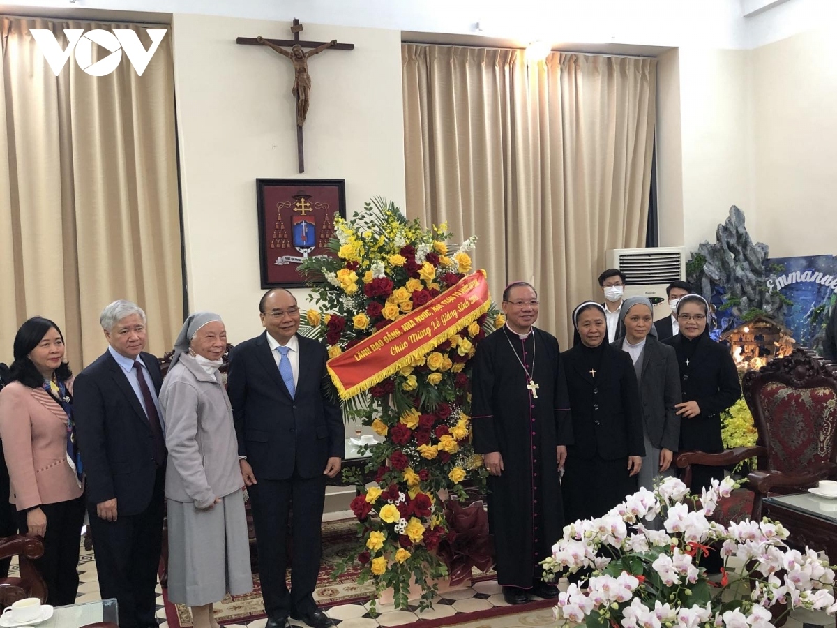 President Nguyen Xuan Phuc presents a bouquet of flowers to Joseph Vu Van Thien, Archbishop of the Hanoi Archdiocese, on Christmas and new Year 2022.