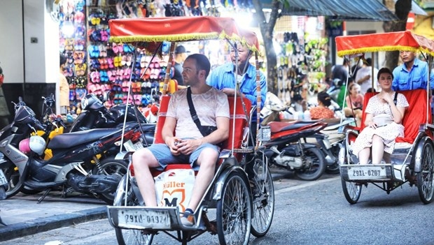 Foreign tourists enjoy a cyclo tour of Hanoi.