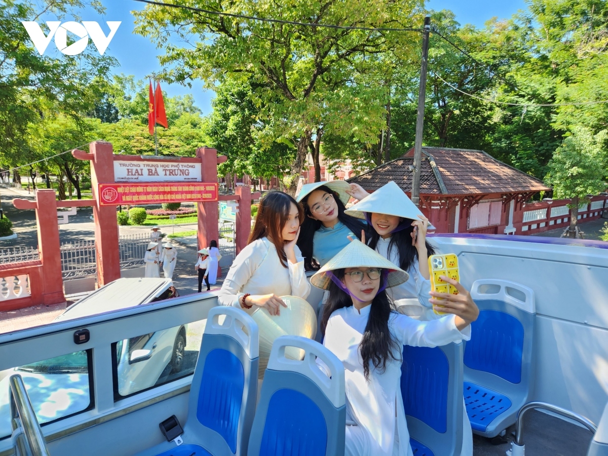 A group of tourists pose for check-in photos in front of Quốc Học Huế, also known as Hue High School for the Gifted.