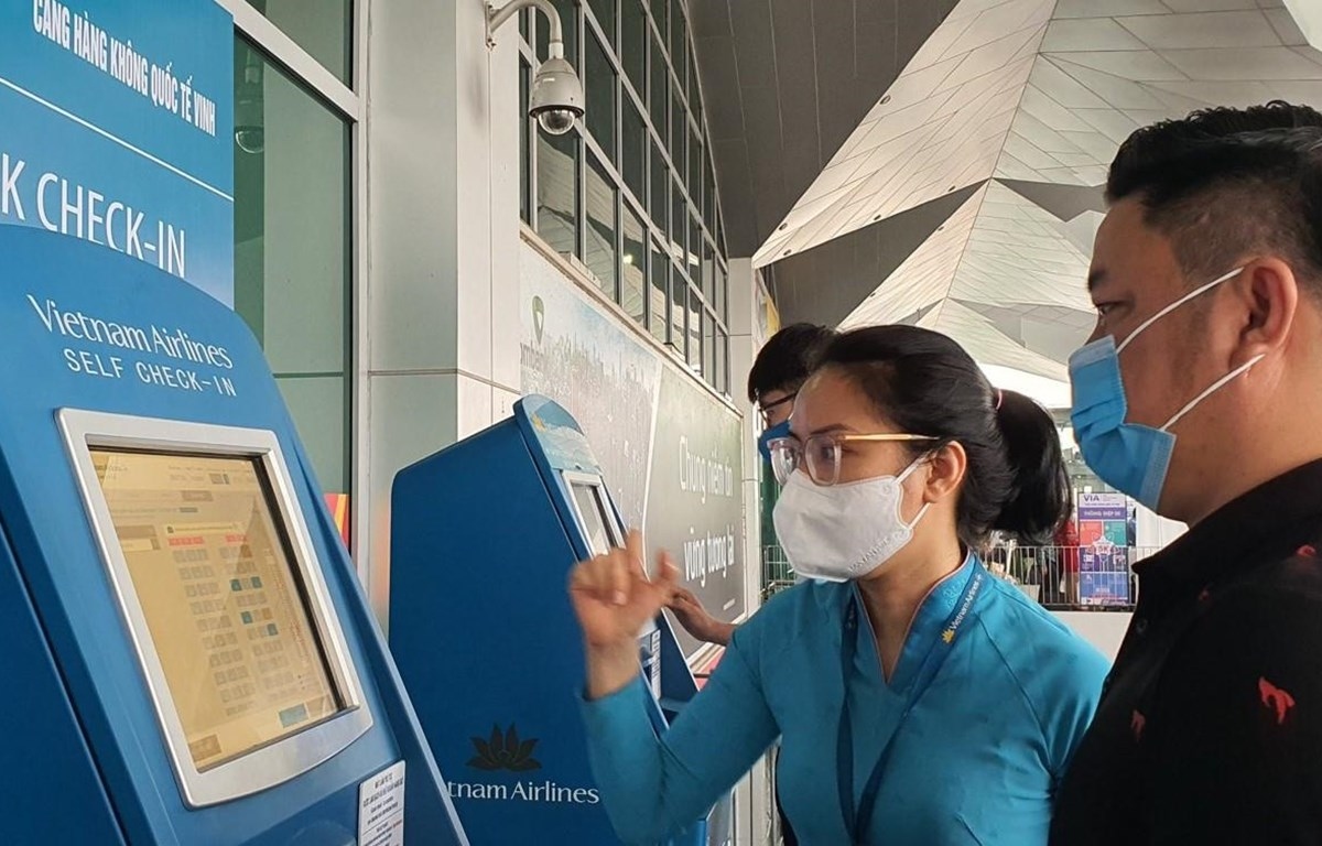 A Vietnam Airlines staff helps passengers at online check-in counters (Photo: VNA)