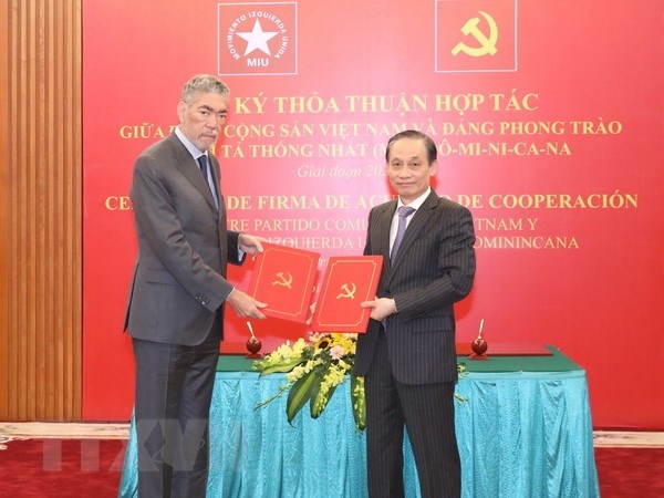 Le Hoai Trung, member of the Party Central Committee and head of the Party Commission for External Relations, and Miguel Mejia, general secretary of the MIU and minister for Regional Integration Policies of the Dominican Republic, exchange the signed cooperation document in hanoi on February 26. (Photo: VNA)