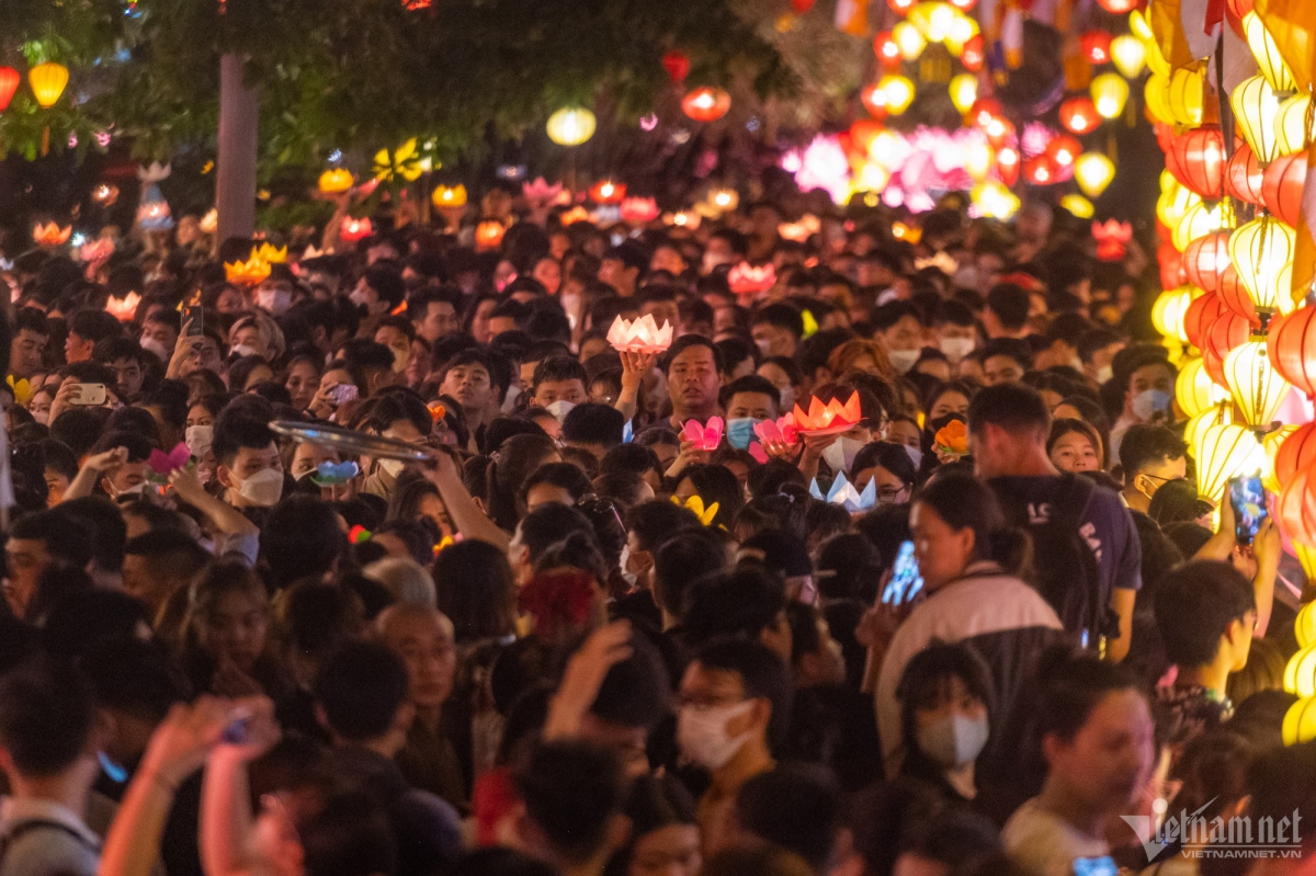 The crowd hold lanterns in front of the pagoda gate.