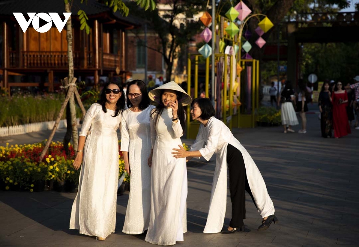 A group of visitors don Ao Dai (traditional long dress) as they pose for a group photo.