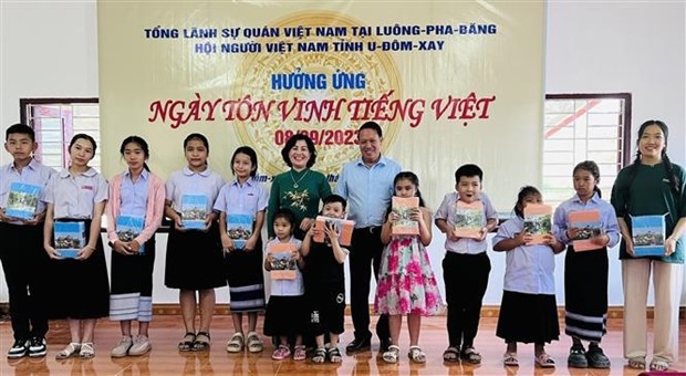 Vietnamese Consul General in Luang Prabang, Kieu Thi Hang Phuc (in traditional long address) takes photo with disadvantaged students in Oudomxay province of Laos.