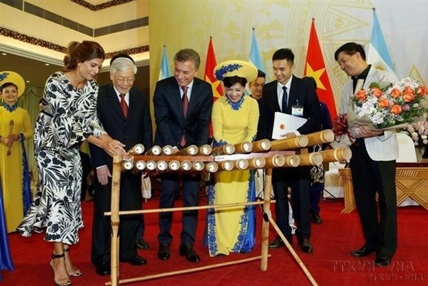 Argentine President Mauricio Macri tries his hand at playing a Vietnamese traditional music instrument during his Vietnam visit in 2019 (Photo: VNA)