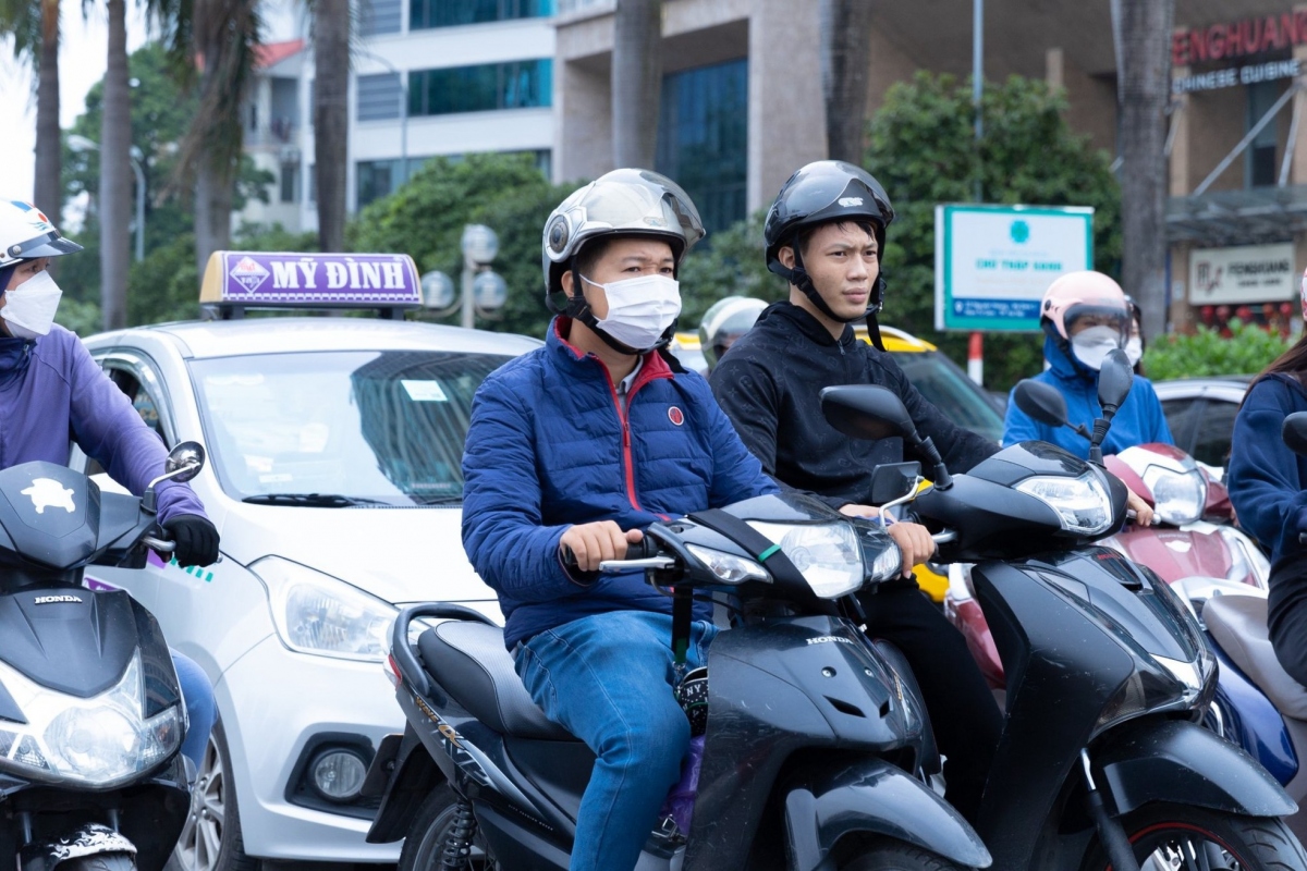 Locals wrap up in thick layers of clothing and put on face masks in a bid to avoid the bitterly cold breeze whilst travelling by motorbike around the capital.