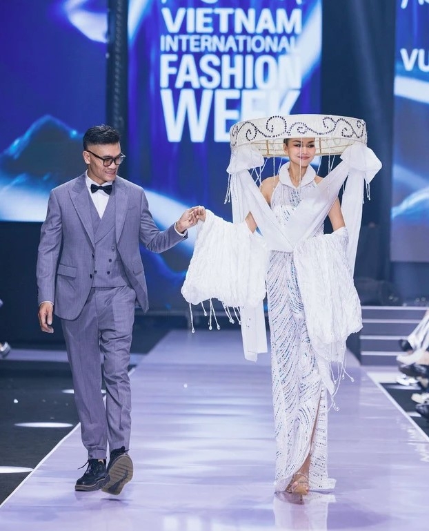 Designer Vu Viet Ha (L) joins with model Thanh Hang at the event.