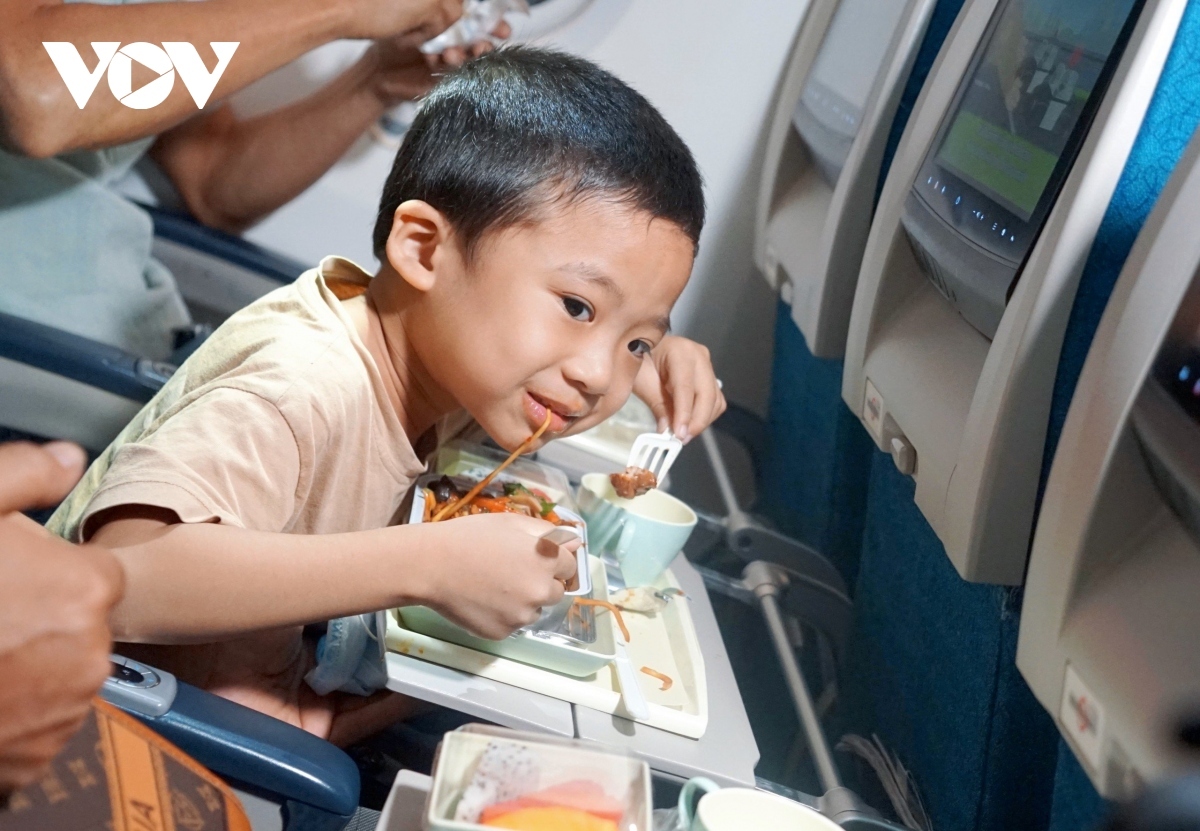 A child enjoys his meal on his first flight with his family as they prepare for a Tet reunion.