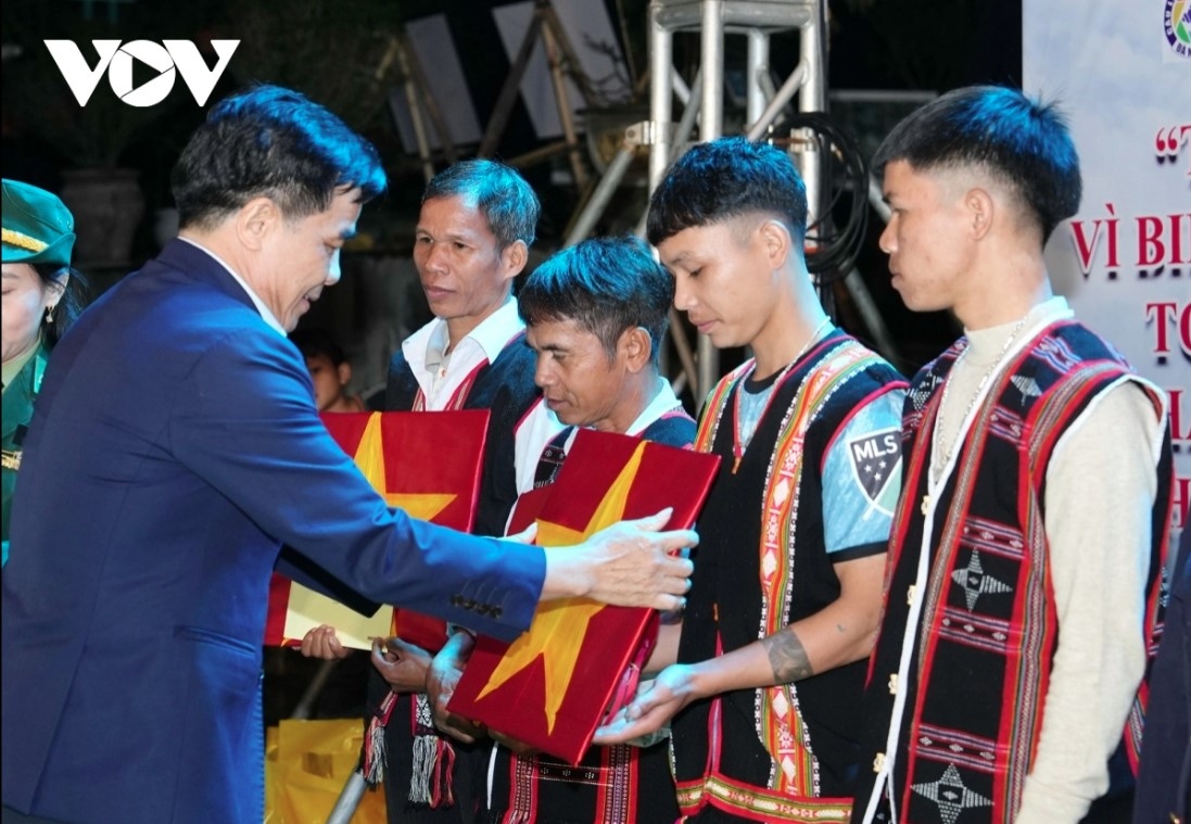 Soldiers present national flags to people in the Vietnam-Laos border areas.