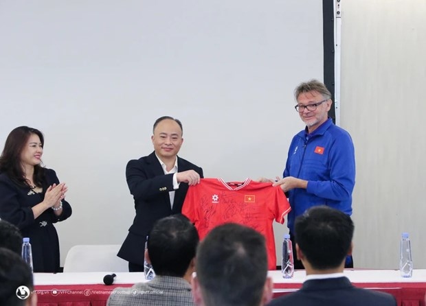 Head coach Philippe Troussier (R) presents a jersey with Vietnamese players' signatures to the Vietnamese Embassy in Qatar on January 12. (Photo: Vietnam Football Federation)