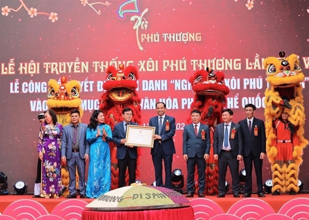 Representatives of Tay Ho district's authorities receive the certificate recognising the craft of cooking sticky rice in Phu Thuong village as a national intangible cultural heritage