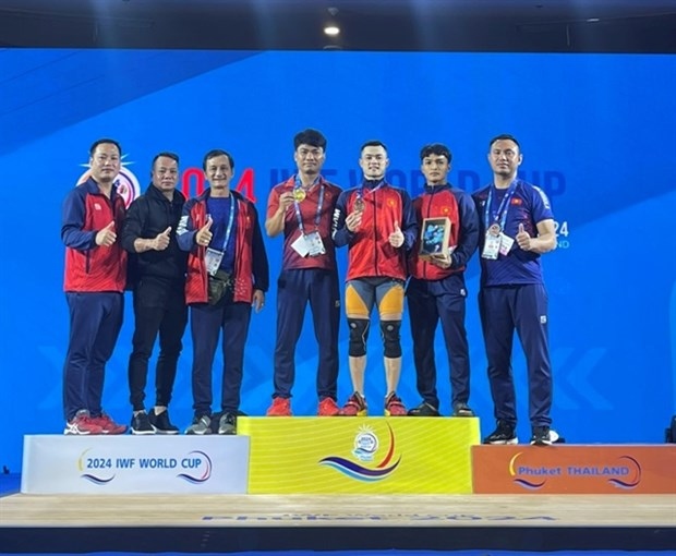 Lai Gia Thanh (third, right) and Vietnamese coaches and staff pose for a photo after he wins the World Cup gold medal on April 1 in Thailand.