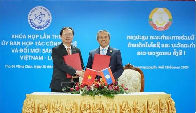 Vietnamese Minister of Science and Technology Huynh Thanh Dat (L) and Lao Minister of Technology and Communications Boviengkham Vongdara exchange the minutes of the first session of the Vietnam-Laos Committee for Cooperation in Technology and Innovation in Vientiane