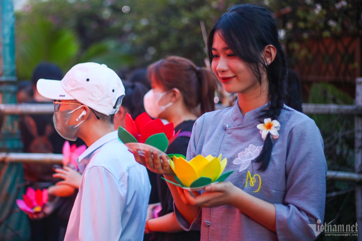 A young girl joins the crowd to hold lanterns in front of the pagoda gate.