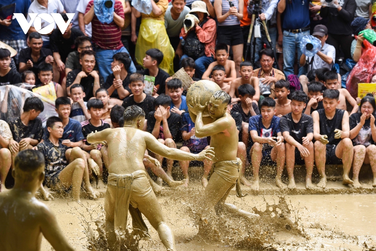 The game is played on a muddy field with 16 local young men divided into two teams.