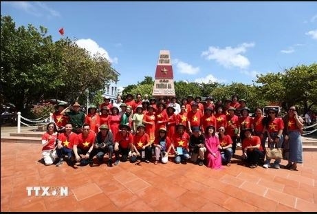 The overseas Vietnamese delegation in a group photo at the landmark of the Truong Sa.