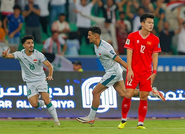 Aymen Hussein (white, centre) celebrates Iraq's third goal, while Pham Tuan Tai (12, red) looks on. (Photo: VFF)