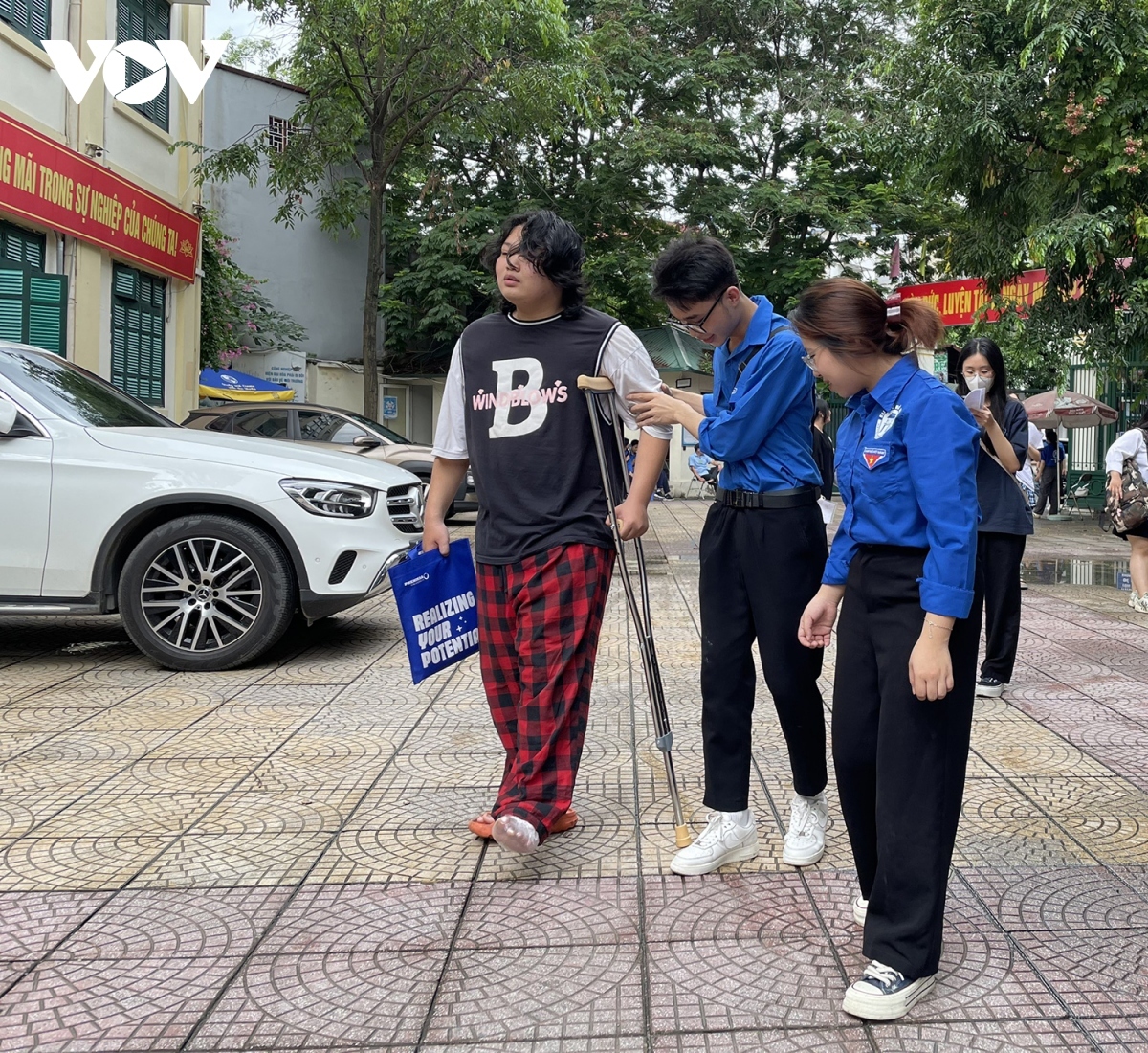 Volunteers support a contestant with a broken leg at an exam council in Hanoi’s Thang Long High School.