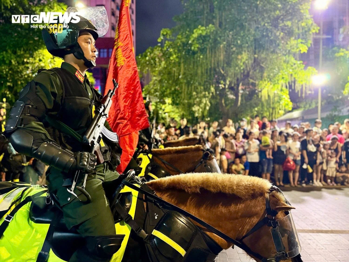The police officers, armed with AK guns, walkie-talkies and batons, march slowly along the pedestrian street.