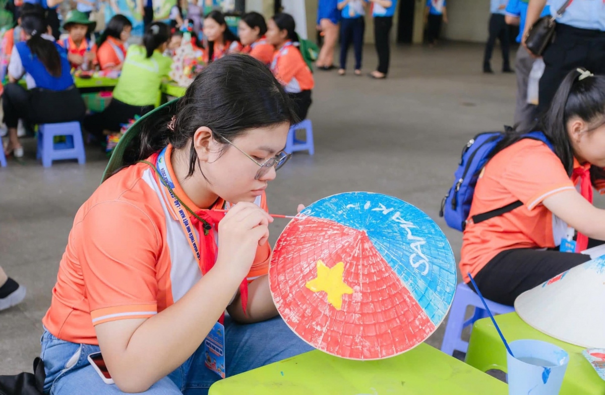 A child draws a conical hat with the words Vietnam and Samaki, which means solidarity in Cambodian language.