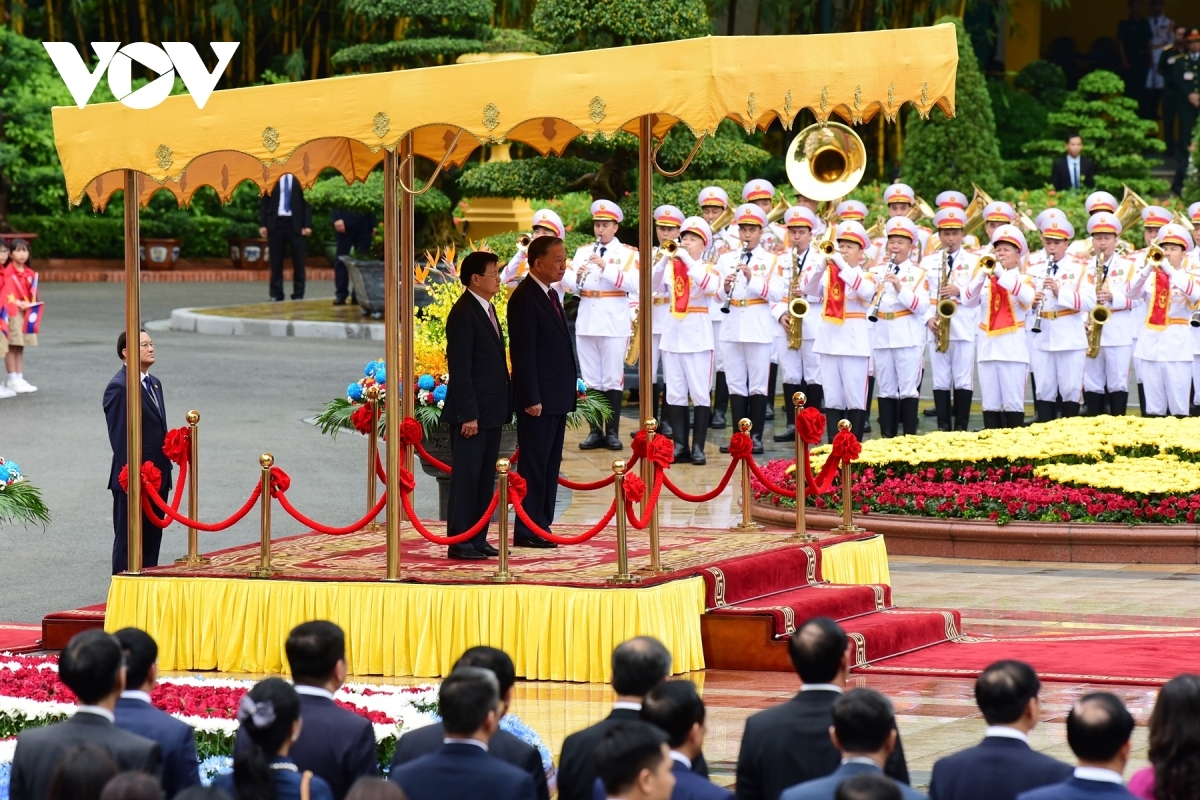 To Lam invites Thongloun Sisoulith to the podium of honour to render the flag salute.