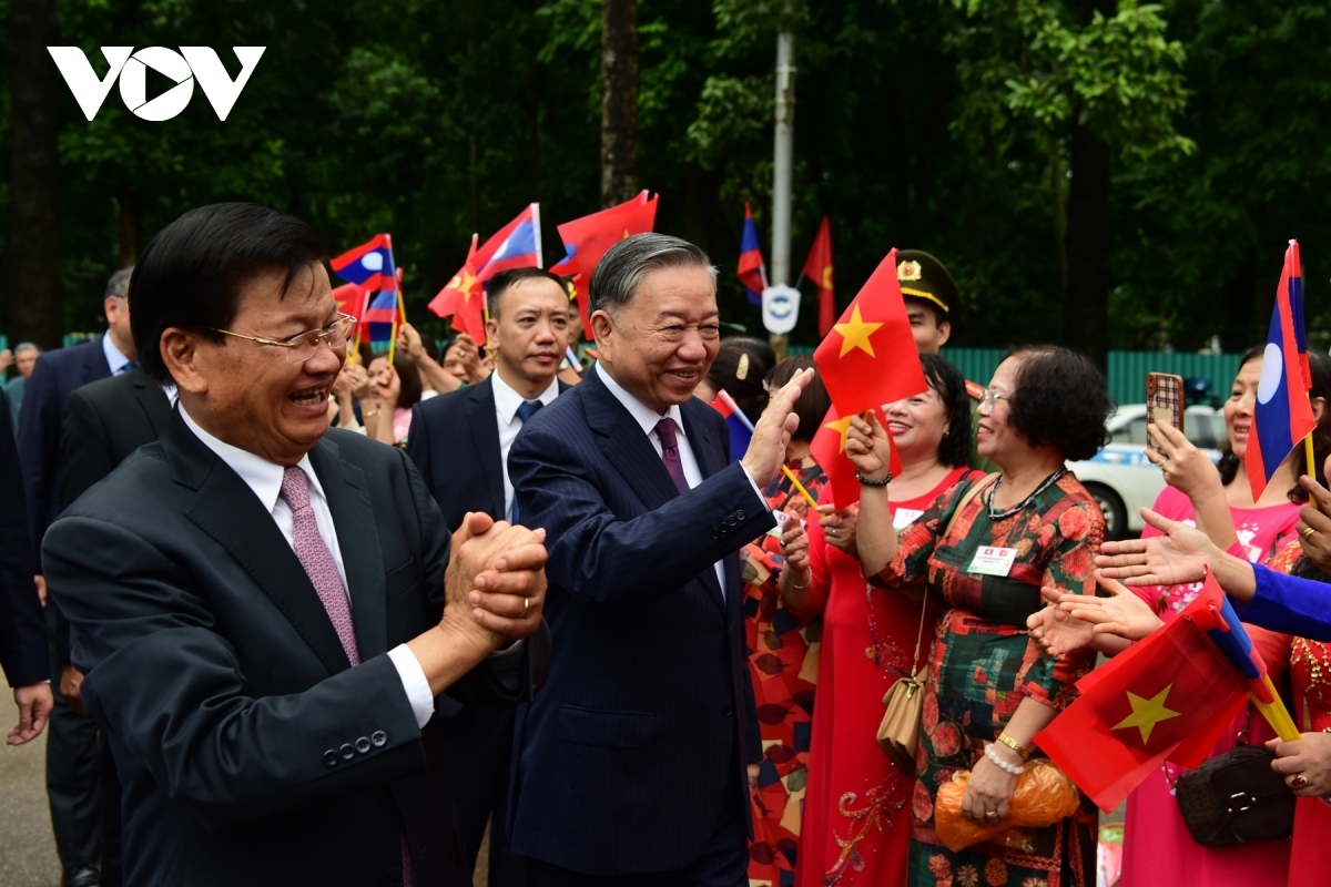 Residents of Hanoi capital line the street, waving flags and flowers to welcome the two leaders.