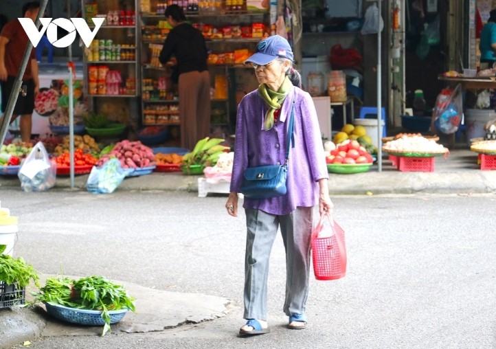 An old woman wraps up tight in a hat and scarf to deal with the cold weather.