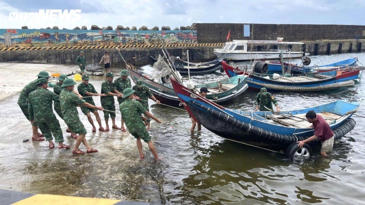 Soldiers help the fishermen to move their boats and equipment to safe areas.