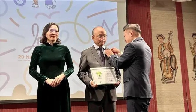 UEVF President Nguyen Phan Bao Thuy presents insignias to Vietnamese Ambassador to France Dinh Toan Thang and Ambassador Nguyen Thi Van Anh