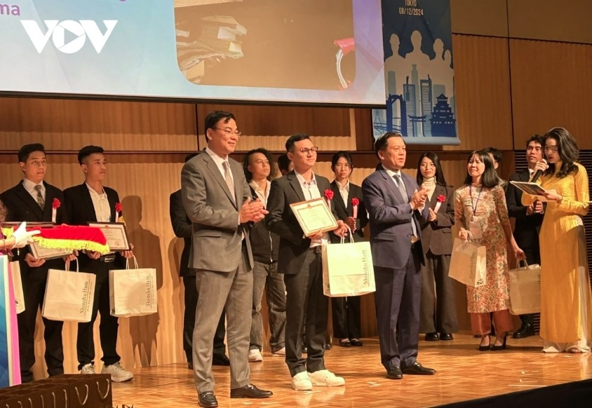 Ambassador Pham Quang Hieu (left) and Deputy Minister of Labor, War Invalids and Social Affairs, Nguyen Ba Hoan present certificates of merit to Vietnamese interns.