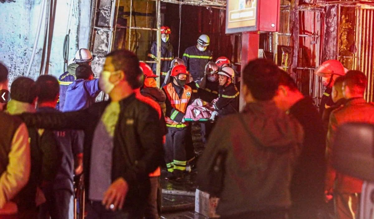 Firefighters move dead bodies out of the coffee shop burned down by the fire