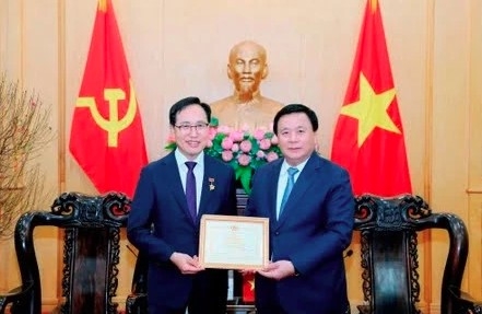Politburo member, President of the Ho Chi Minh National Academy of Politics (HCMA) and Chairman of the Central Theory Council Nguyen Xuan Thang (R) presents the HCMA's insignia "For the cause of political theory education and training" to Choi Joo Ho, General Director of Samsung Vietnam. (Photo: VNA)
