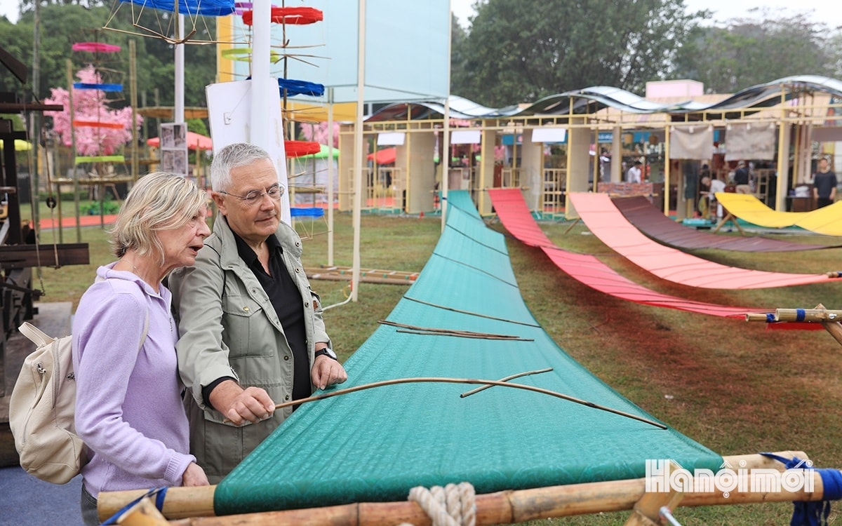 Foreign tourists find out about the process of making products in Van Phuc silk village.