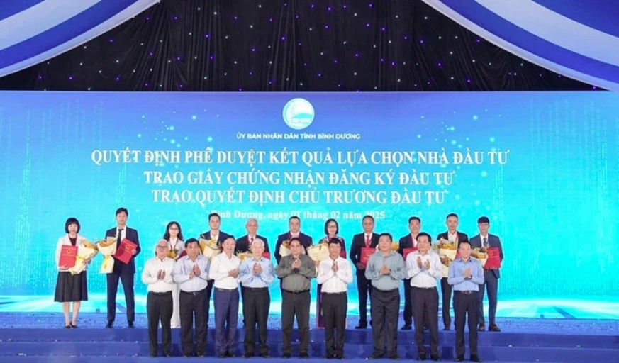 Prime Minister Pham Minh Chinh (centre, first row), and leaders of Binh Duong province handover investment certificates to enterprises. (Photo: daibieunhandan.vn)