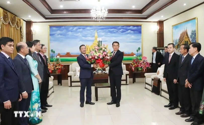 Vietnamese Ambassador to Laos Nguyen Minh Tam delivers Party General Secretary To Lam's bouquet of flowers to a representative of the Lao People's Revolutionary Party on its 70th anniversary. (Photo: VNA)