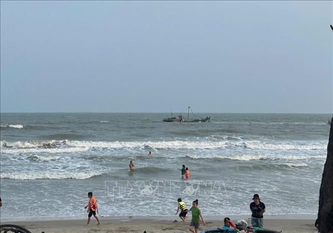 Local residents discover a half-sunken fishing boat situated about 300 metres from shore. (Photo: VNA)