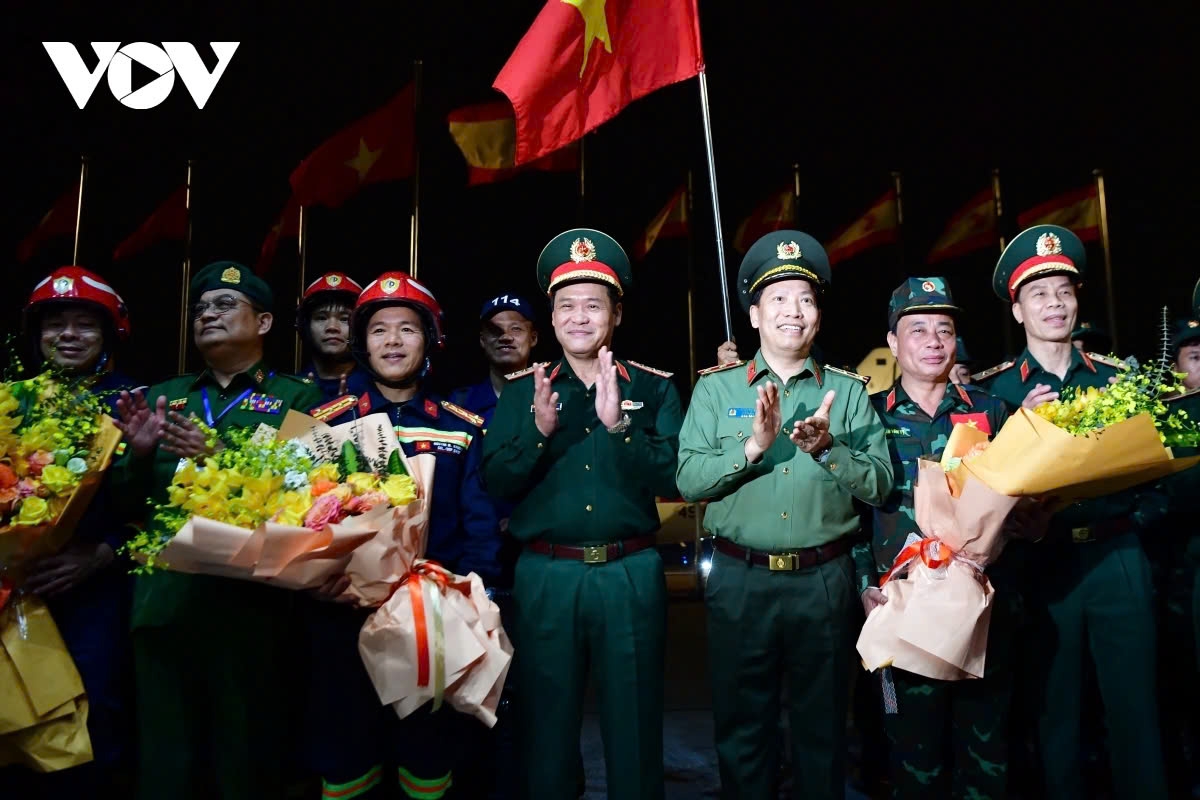 Senior Lieutenant General Vu Hai San, Deputy Minister of National Defence, and Lieutenant General Le Van Tuyen, Deputy Minister of Public Security, welcome the delegation at the airport, presenting them flowers to congratulate the 106 officers and professional soldiers on successfully completing their mission.
