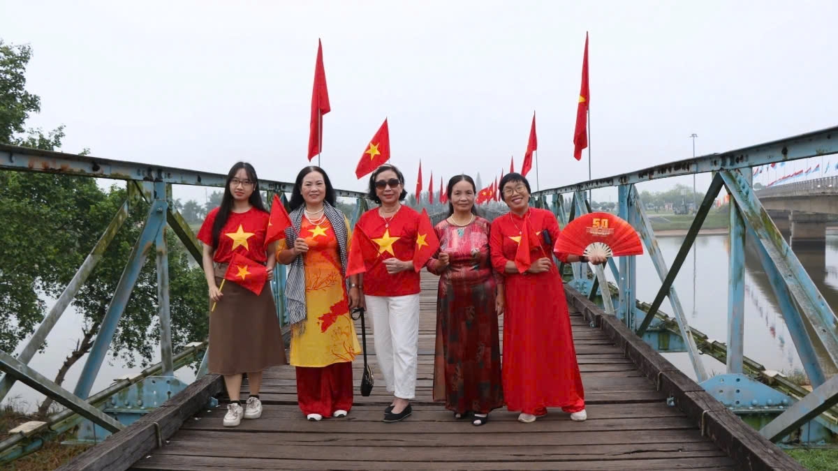 People joyfully take photos on the historic Hien Luong Bridge, capturing memories at this iconic site.